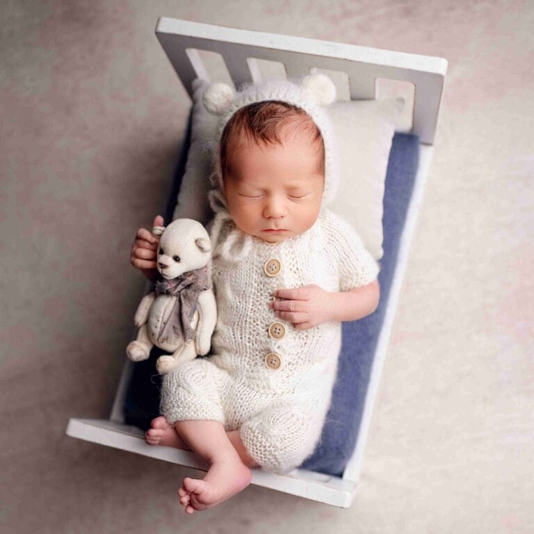 Detail na postýlce: „Minimalistické focení miminek Brno, novorozeně s plyšákem v bílé dřevěné postýlce.“