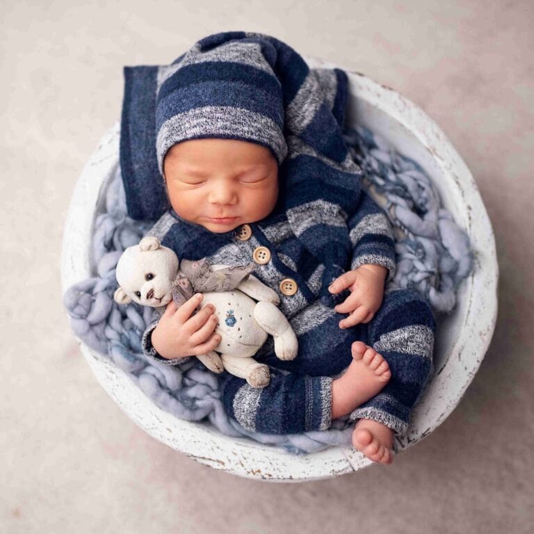 Modrá zavinovačka: „Klasické newborn focení Praha, novorozeně v modré pruhované zavinovačce s pletenou hračkou v košíku.“