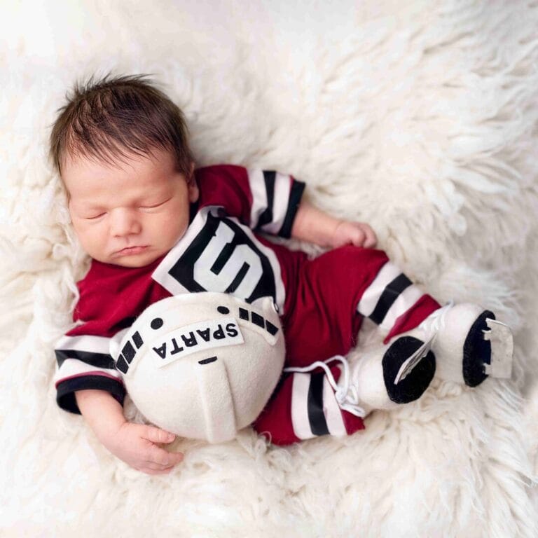 Newborn focení pro fanoušky – malé miminko v hokejovém dresu s pukem