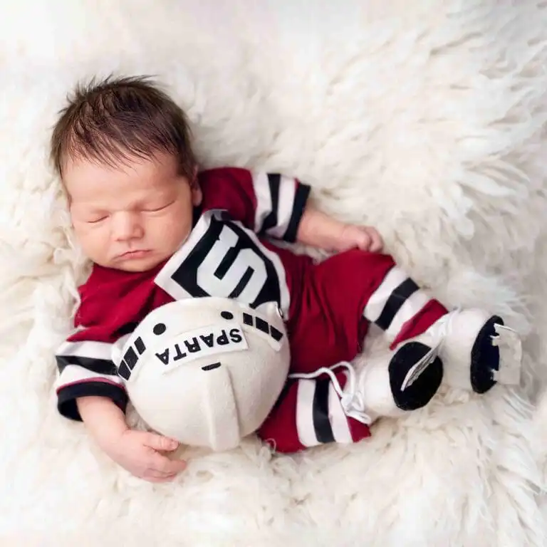 Newborn focení pro fanoušky – malé miminko v hokejovém dresu s pukem